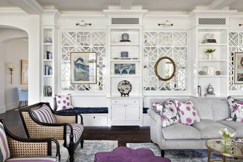 dzīvojamā istaba, pelēks dīvāns, purpursarkani un balti dekoratīvie spilveni, balti glabāšanas skapji, purpursarkana pufa