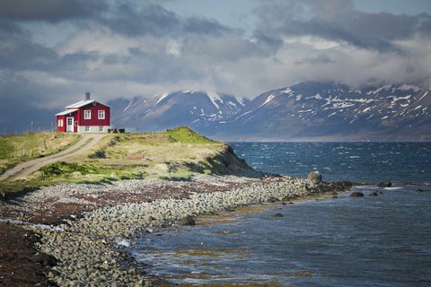 sarkana māja blakus fjordam ziemeļatlantijā