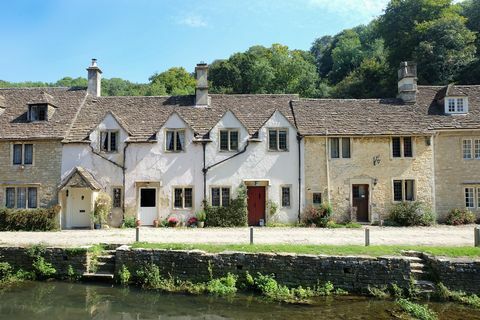 skaistas mājas Bibury ciematā zem saules gaismas Lielbritānijā