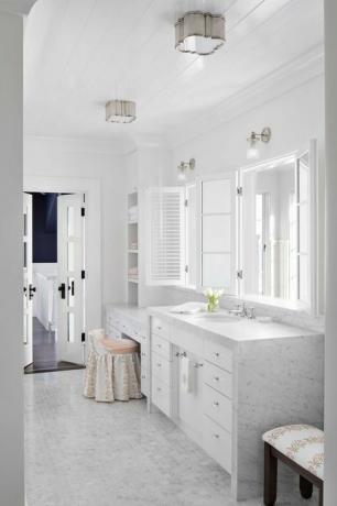 marmora vannas istaba, marmora virsmas, mazas marmora sešstūra flīzes, balti skapji, balts spogulis, tualetes sēdeklis un krēsls