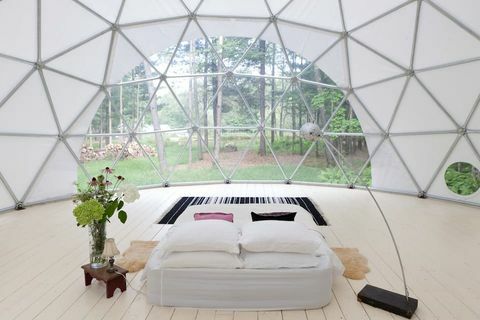 ģeogrāfiskā kupola interjers ar gultu un lampu centrā