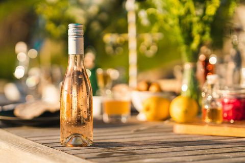 neatvērta pudele auksta sārta vīna uz Jāņu pusdienu galda zviedrijā fokusā uz pilošo svaigo pudeli priekšplānā