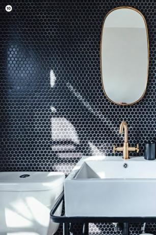 vannas istabas tualete ar zilu flīžu sienu un ovālu spoguli