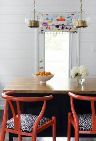 sarkani krēsli baltā virtuvē ar apšuvuma sienām 
