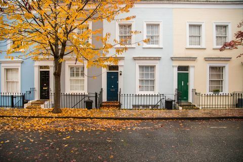 Notinghilas apkaimes mājas ar pasteļkrāsas fasādi ar jauku kompozīciju bez automašīnām un koku ar rudens lapām uz zemes Londonas pilsētā. Apvienotā Karaliste, Eiropa.