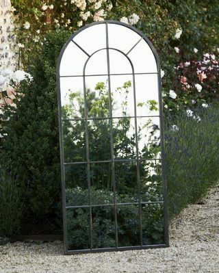 Liels melnā metāla arkveida dārza spogulis