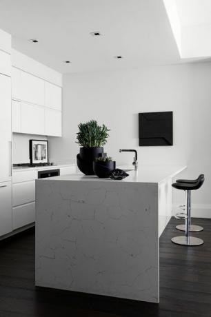 virtuve, baltas marmora virsmas skapji, melni bāra krēsli