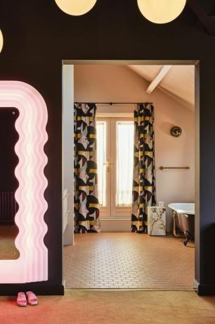 privāta vannas istaba. pieskaņoti aizkari, atvērtas durvis un klusināta karameļu krāsu shēma savieno divas istabas spogulis vintage Ettore Sottsass flīzes Winckelmans