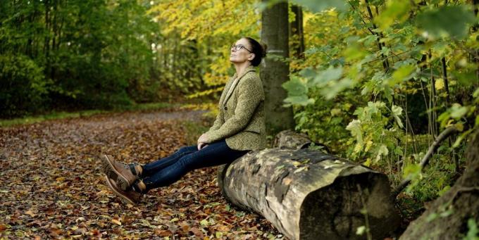 nobriedusi sieviete, kas sēž uz koka stumbra rudens mežā